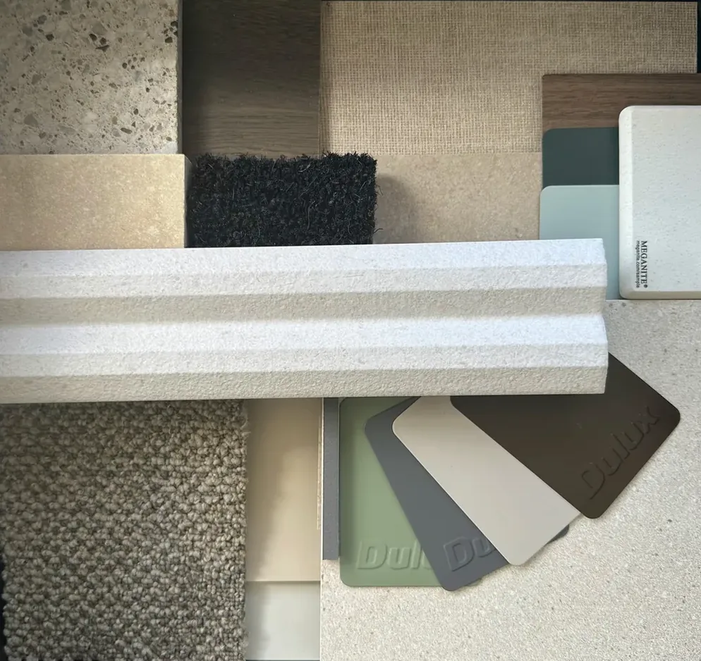 Finishes board: speckled stone tile, dark timber, woven wall tile, charcoal entry mat, a fluted white tile, carpet plank and green, grey, cream and brown paint chips